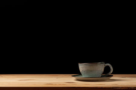 Handmade cup with coffee on the table. Countertop made of wood. Coffee beans. Black background.の写真素材