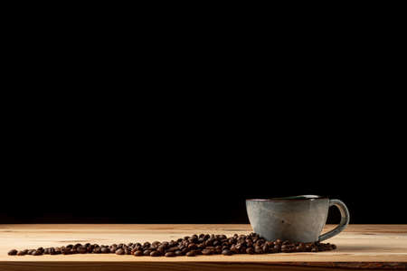Handmade cup with coffee on the table. Countertop made of wood. Coffee beans. Black background.の写真素材