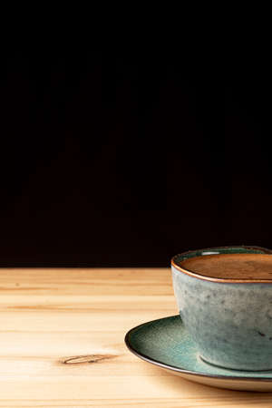 Handmade cup with coffee on the table. Countertop made of wood. Coffee beans. Black background.の写真素材