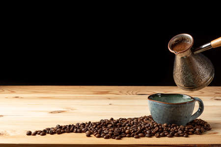 Handmade cup with coffee on the table. Countertop made of wood. Coffee beans. Black background.の写真素材