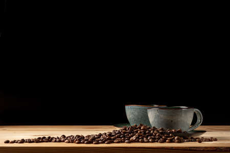 Handmade cup with coffee on the table. Countertop made of wood. Coffee beans. Black background.の写真素材