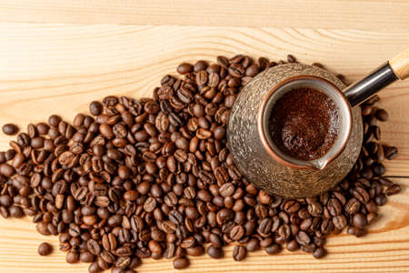 Copper cezve with coffee on the table. Freshly brewed coffee. Countertop made of wood. Coffee beans. Freshly fried arabica.の写真素材