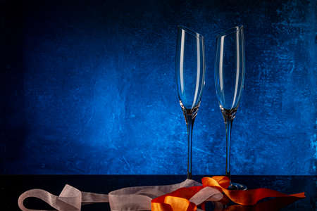 Two glasses for champagne on a black mirror surface. Blue background Concrete wall. Black glass. Crystal glassの写真素材
