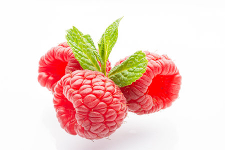 Ripe raspberries on a white background. A sprig of fresh mint. Berries. Garden raspberries. White...