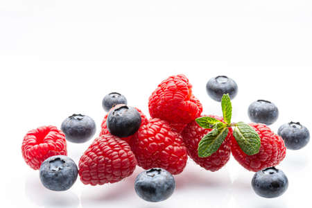 Ripe wild berries on a white background. A sprig of fresh mint. Garden raspberries. Ripe blueberries. White background. Red. Blue. Isolated.の写真素材
