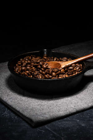 Freshly roasted coffee beans in a cast iron skillet. Linen napkin. A natural stone. Dark background.の写真素材