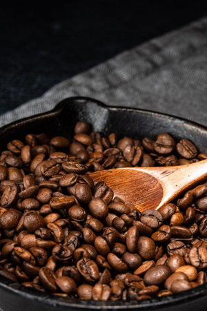 Freshly roasted coffee beans in a cast iron skillet. Linen napkin. A natural stone. Dark background.の写真素材