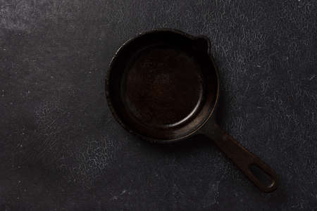 Empty black cast iron frying pan on a dark graphite background. Light linen towel.の写真素材