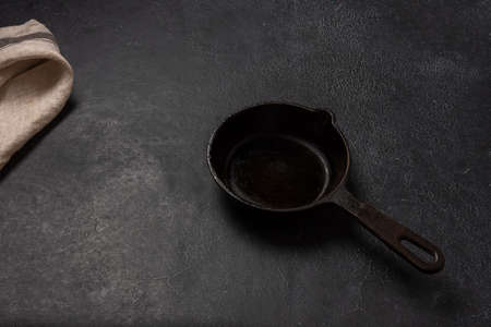 Empty black cast iron frying pan on a dark graphite background. Light linen towel.の写真素材