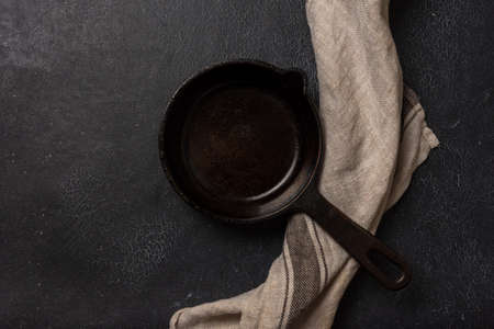 Empty black cast iron frying pan on a dark graphite background. Light linen towel.の写真素材