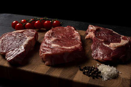 Raw marbled beef steak on a wooden cutting board. Top class marbled beef. Graphite-colored table top.の写真素材