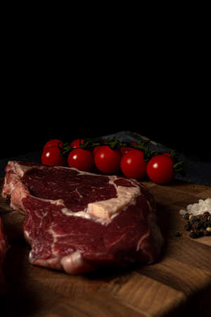Raw marbled beef steak on a wooden cutting board. Top class marbled beef. Graphite-colored table top.の写真素材