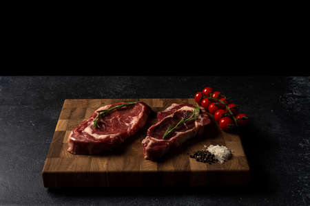 Raw marbled beef steak on a wooden cutting board. Top class marbled beef. Graphite-colored table top.の写真素材