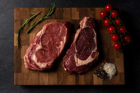 Raw marbled beef steak on a wooden cutting board. Top class marbled beef. Graphite-colored table top.の写真素材