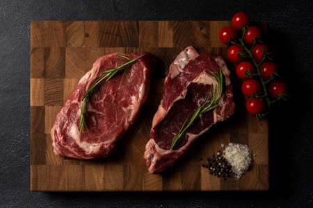 Raw marbled beef steak on a wooden cutting board. Top class marbled beef. Graphite-colored table top.の写真素材
