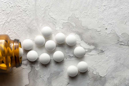 A handful of pills scattered on the table. A vial of medicines. Marble surface. Medicines.の写真素材