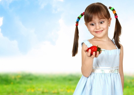 Funny surprised child girl with strawberry, field on background の写真素材