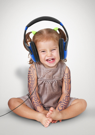 Funny child girl with tatoo listening music in headphonesの写真素材