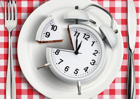 Time to eat concept, cut clock on plateの写真素材