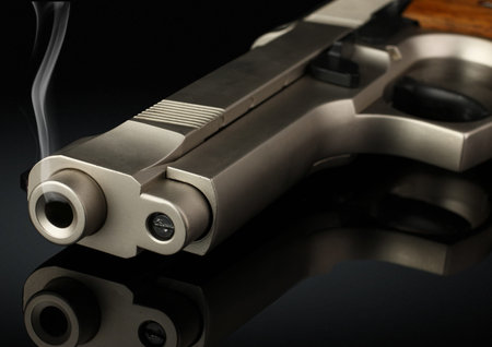 Closeup of handgun with smoke barrel on black, soft focus