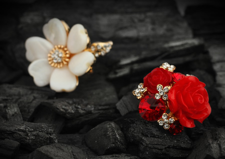 Few jewelry rings with diamonds, gems and pearl on black coal backgroundの写真素材