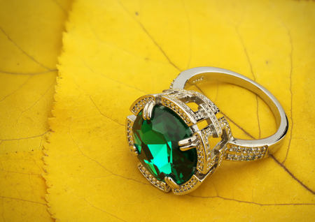 Jewelry ring with gem on yellow leaves  background, copy spaceの写真素材