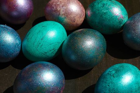 Easter colored eggs in the center on a dark wooden background, top view, close-upの写真素材