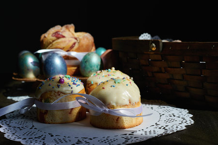 Easter table with multi-colored eggs, Easter cakes, cupcakes on a white lace napkin, kraffins and a...