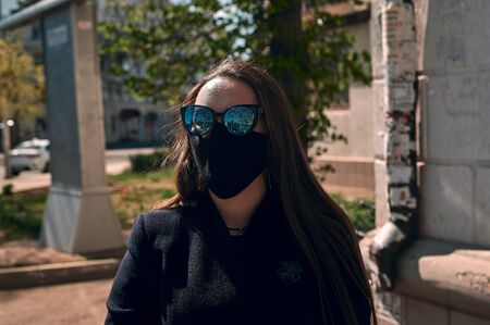 masked girl against coronavirus walking the city streets on a sunny dayの写真素材