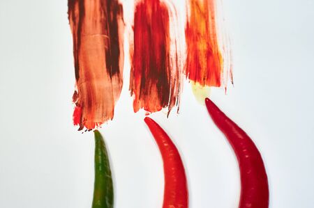peppers on a white background with multi-colored paintの写真素材