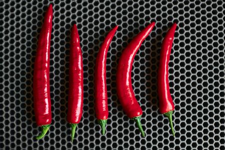 red sharp chili peppers vertically top close up against a dark backgroundの写真素材