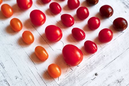 five types of cherry tomatoes on a light wooden background from above close upの写真素材