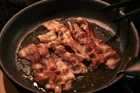 Fried crispy bacon in a close-up pan on top horizontallyの写真素材