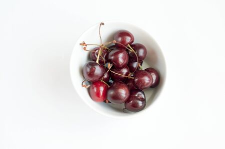 Cherry in a white plate on a white backgroundの写真素材