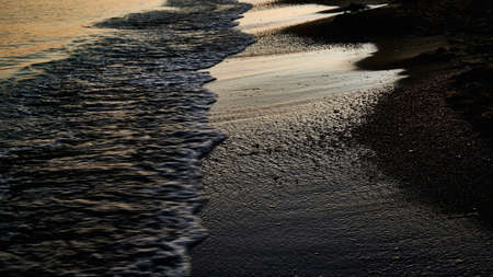 sea foam, beach line at sunset, wet sand, backgroundの写真素材