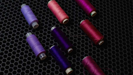 Multi-colored sewing threads diagonally against a dark background from above close-up. High quality photoの写真素材