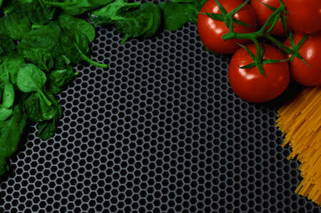 spinach tomatoes on a branch and spaghetti on a dark background close-up background for insertion . High quality photoの写真素材