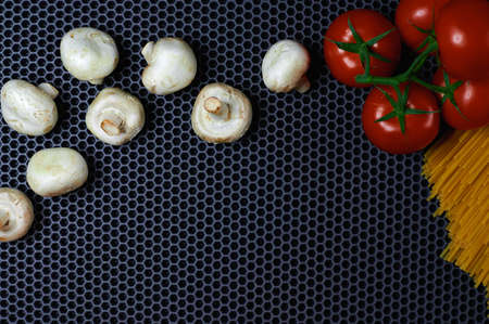 tomatoes on a branch of mushrooms and pasta on a dark background, place for insertion, background, close-up from above. High quality photoの写真素材