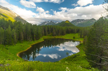 Lake in the Altai Mountains in coniferous forests against the mountains of blue sky with clouds. High quality photoの写真素材