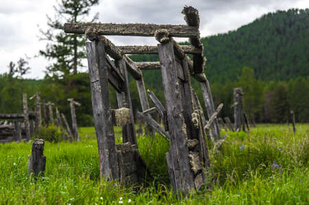 the wooden building collapsed against the backdrop of the mountains.の写真素材