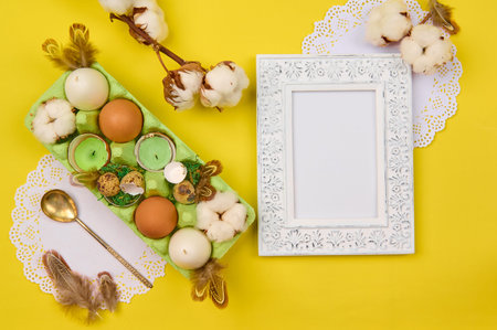easter decor of eggs, quail shell, candles with feathers and moss in a box on an empty background...
