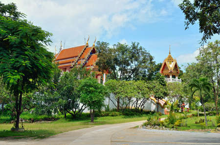 Beautifully decorated Buddhist temple in lush green vegetation against the blue sky.の写真素材