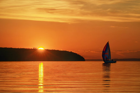 yacht sails against the orange sunset, coastlineの写真素材