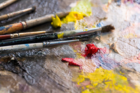 Set of different brushes and oil paints to paint scattered on a dark wooden table top viewの写真素材