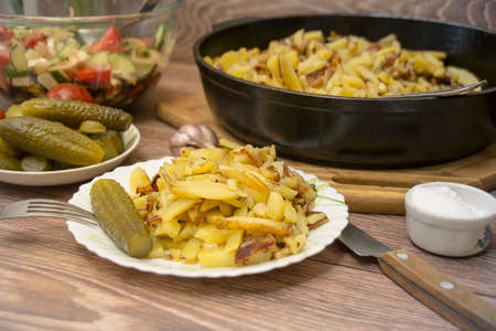 Russian national cuisine: fried potatoes with pickled cucumber, garlic.の写真素材