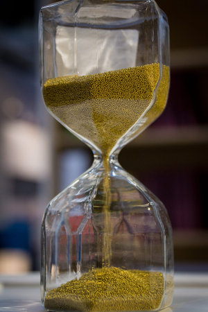 A large hourglass with bright beautiful sand on a wooden table.の写真素材