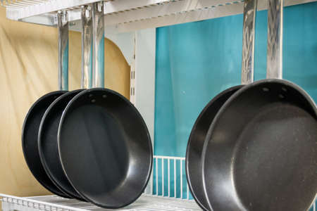 Empty frying pans hang on the shelf. Dishes.の写真素材