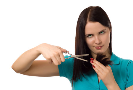 thoughtful young brunette with scissors cutting hair (isolated on white)