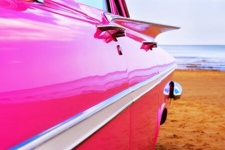 Classic pink car at beachの写真素材