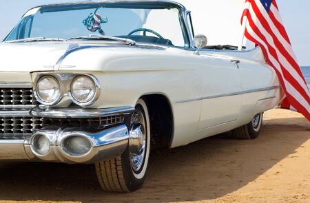 Classic white car at the beach with American flagの写真素材